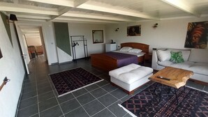 Une chambre d’hôtel avec un lit, un canapé, une table basse, une télévision et une salle de bain visible au fond.