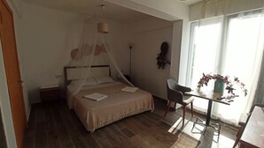 Une chambre à coucher avec un lit, une table de chevet, une chaise et une fenêtre avec des rideaux.