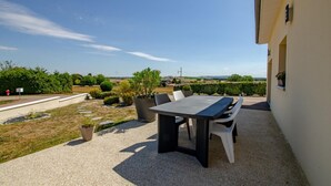 An outdoor patio with a table and chairs, surrounded by potted plants and a view of the countryside. - Chez Mimi - Plessis Barbuise (PLESSIS BARBUISE)