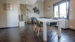 A modern kitchen with a dining area, a staircase, and a large window. - Chez Mimi - Plessis Barbuise (PLESSIS BARBUISE)