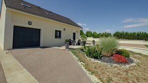 A modern house with a garage, outdoor seating, and a landscaped garden. - Chez Mimi - Plessis Barbuise (PLESSIS BARBUISE)