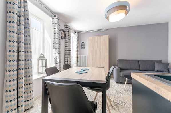 A modern room with a dining table, chairs, a sofa, and a pool table.