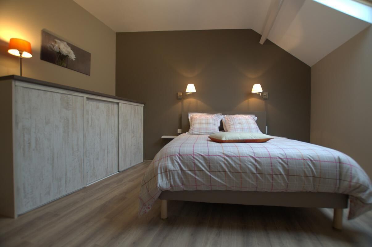 Um quarto com uma cama, luminárias de cabeceira, mesa de cabeceira e um guarda-roupa.