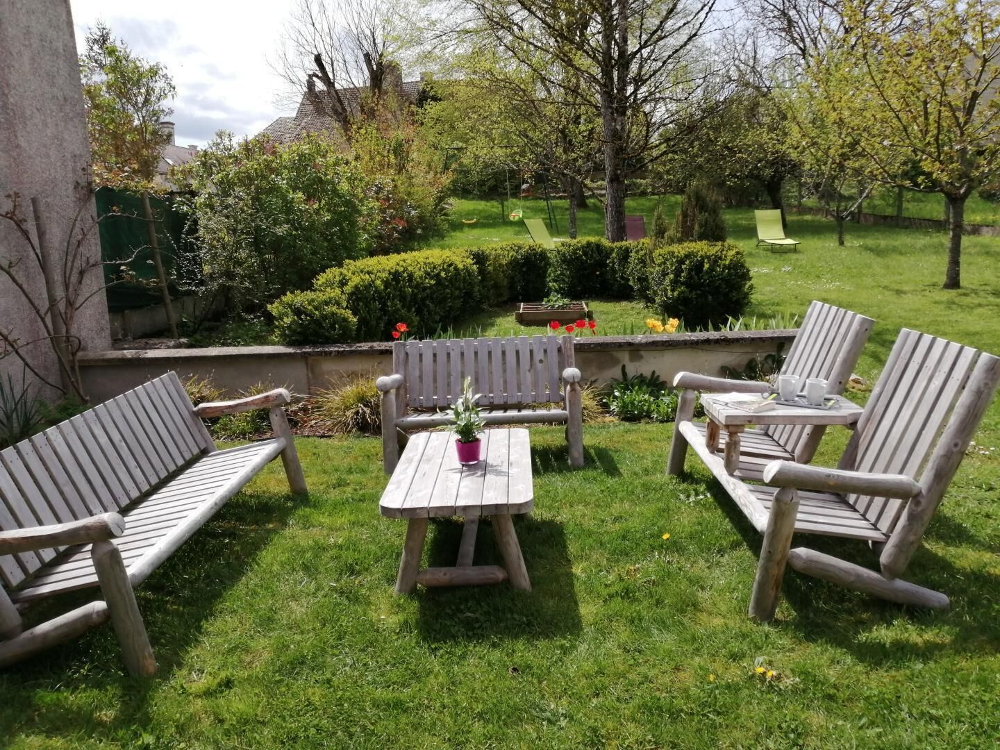 A patio with wooden furniture, a small table, and a potted plant.