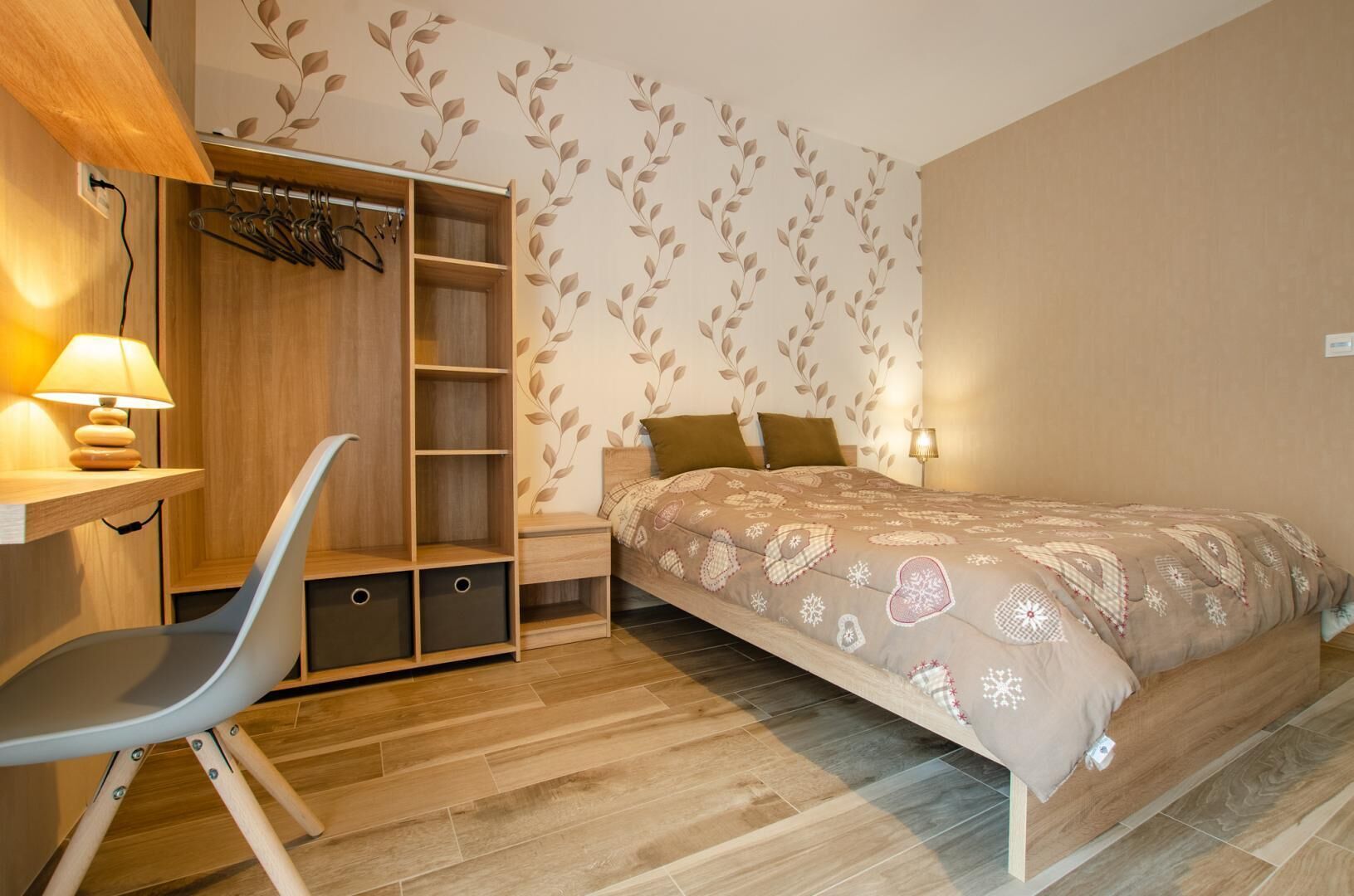 A bedroom with a bed, a wardrobe, a desk, and a chair.