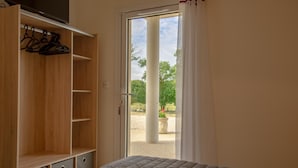 Un dormitorio con una cama, un armario de madera y una puerta que da a un espacio al aire libre.