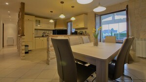A modern kitchen with a central island, pendant lighting, and a view through a large window.