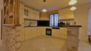 A kitchen with white cabinets, a black oven, and a window with curtains.