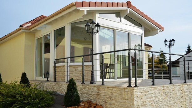 A modern building with large windows, a stone facade, and a metal railing.