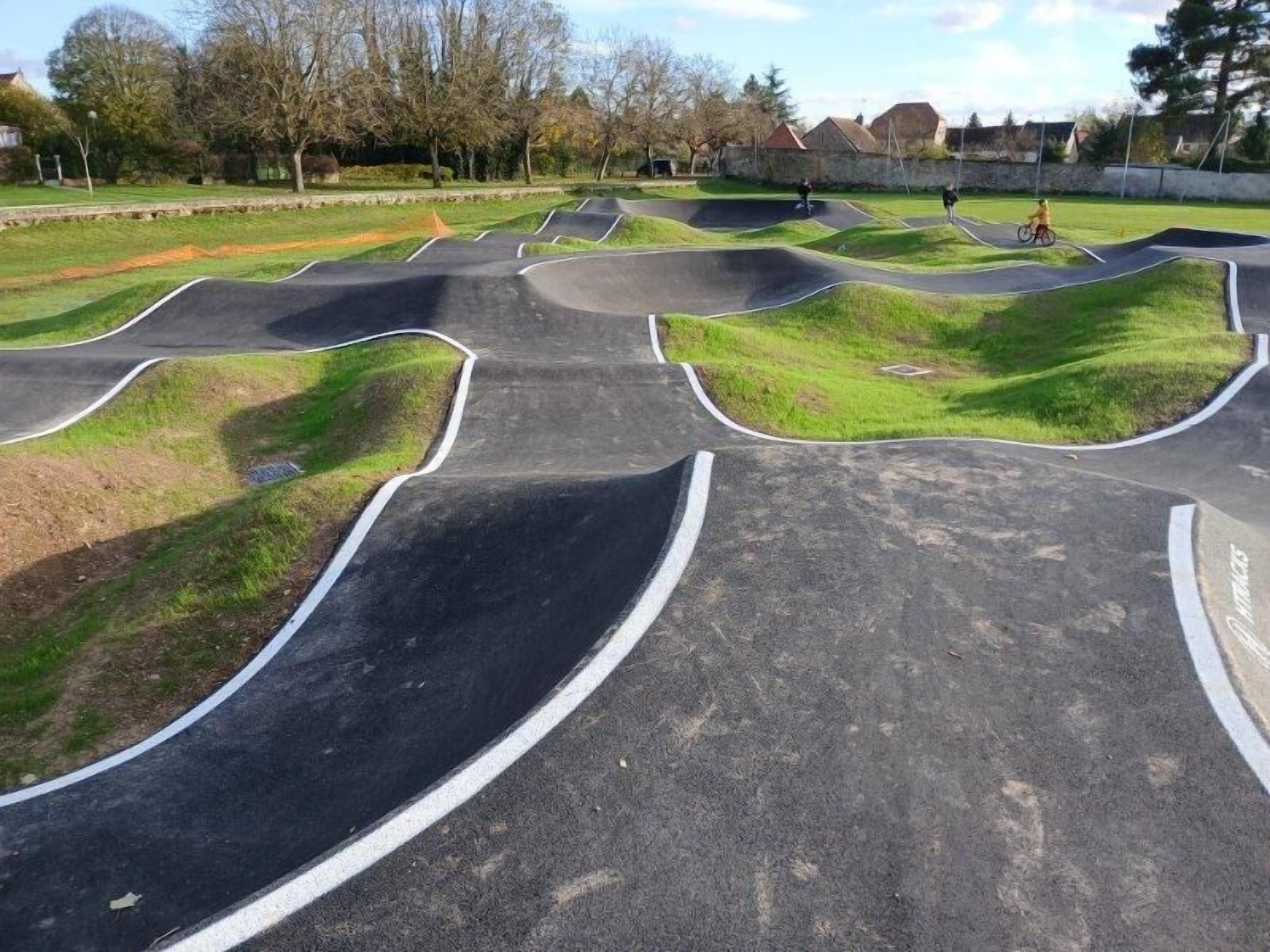 Un parc de patinatge amb diverses rampes i una zona enjardinada.