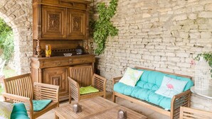 A stone-walled outdoor seating area with wooden furniture, including a sofa and chairs, and a wooden cabinet. - La Clémenceraie - Baroville (BAROVILLE)