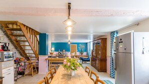 A spacious kitchen with a wooden dining table, a staircase, and a refrigerator. - La Clémenceraie - Baroville (BAROVILLE)