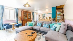 A modern living room with a sectional sofa, a wooden coffee table, and a dining area with a kitchen in the background. - La Clémenceraie - Baroville (BAROVILLE)