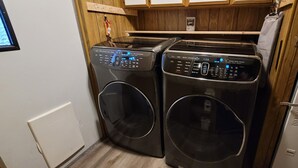A compact laundry room with two front-loading washing machines and a dryer. - Penguin Cabin The Utmost Family Mt Rainier Getaway (Ashford)