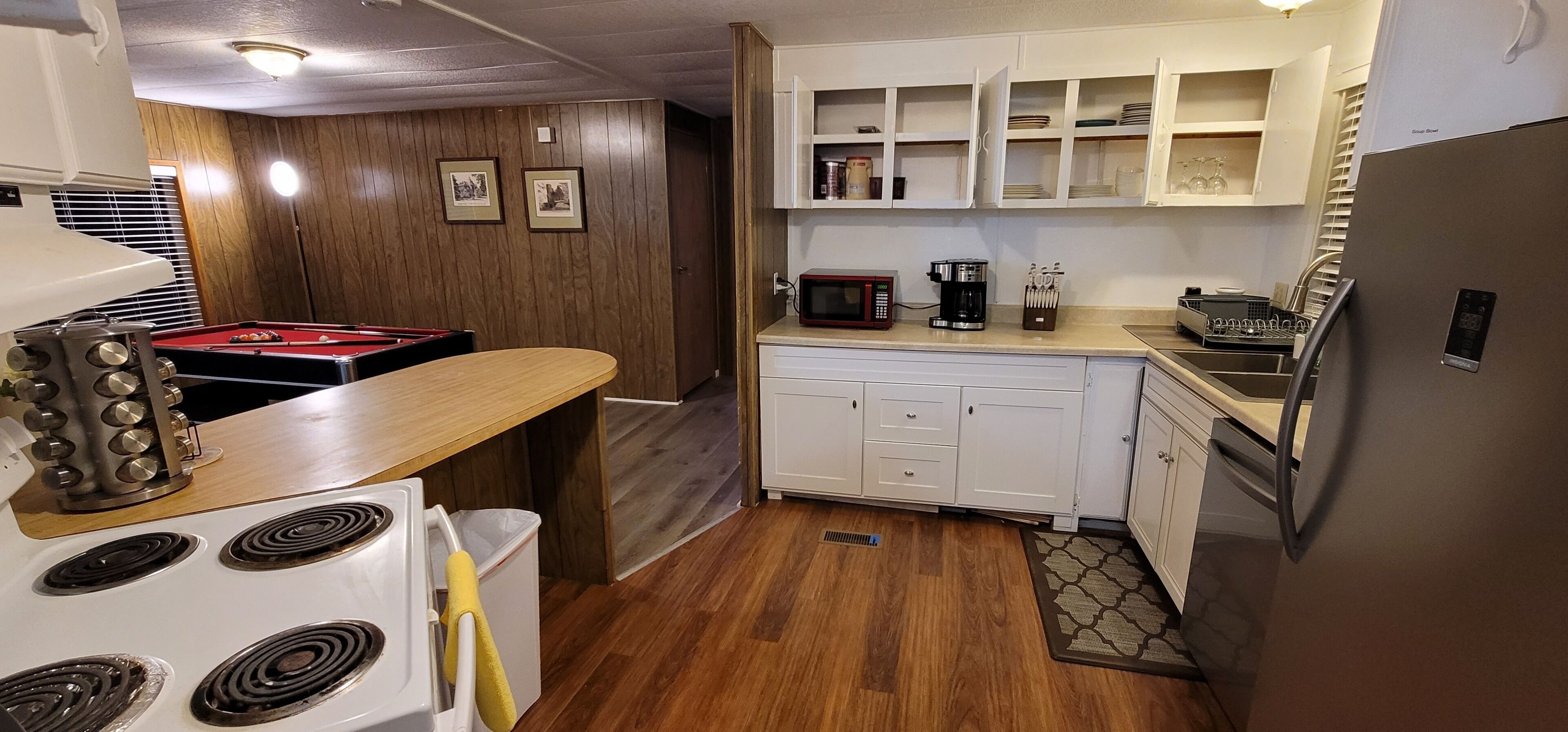 A compact kitchen with a stove, microwave, and coffee maker.