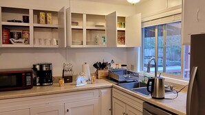 A kitchen with white cabinets, a microwave, a coffee maker, and a sink. - Penguin Cabin The Utmost Family Mt Rainier Getaway (Ashford)