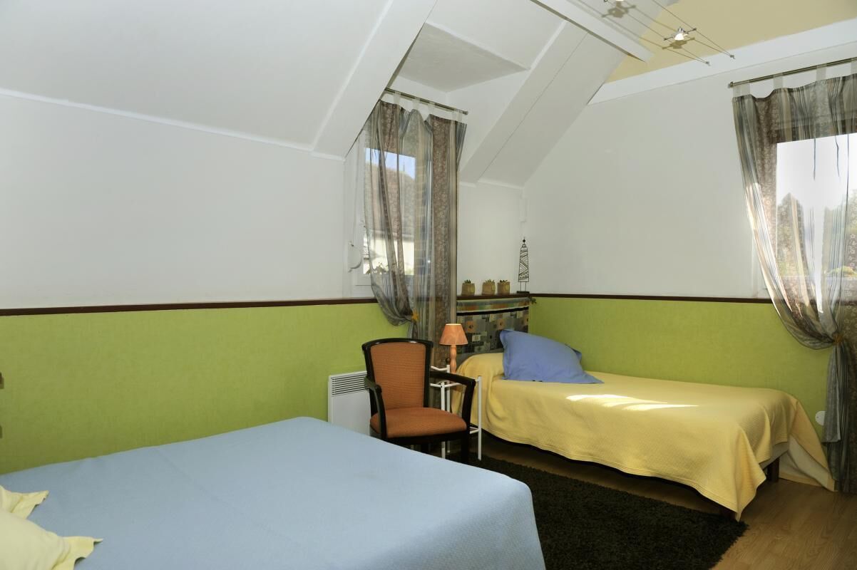Une chambre avec deux lits, une chaise, une lampe et un radiateur.