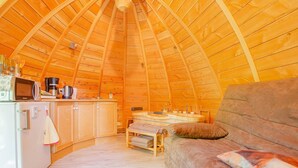 Ein gemütlicher, holzgetäfelter Innenraum mit Küchenzeile, einer Couch und einem Esstisch.