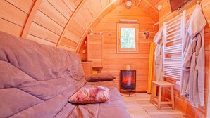 Ein gemütliches Blockhaus-Interieur mit einer Couch, einem kleinen Tisch, einem Kamin und Holzwänden.