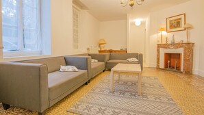 Una sala de estar con sofá, mesa de centro, chimenea y alfombras estampadas.