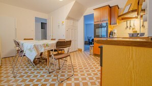 Una cocina compacta con armarios de madera, horno empotrado y comedor con mesa y sillas.