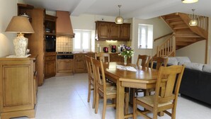 A spacious kitchen with wooden cabinets, a dining table, and a staircase leading to another level.