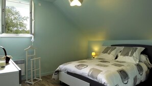 A bedroom with a bed, bedside table, lamp, window, and a hanging light fixture.