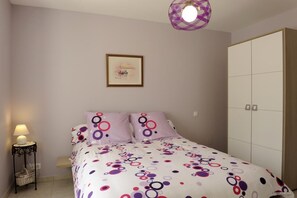 Une chambre à coucher avec un lit, une table de chevet avec une lampe, un tableau encadré au mur et une armoire.
