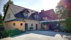 A traditional house with a gravel driveway, multiple windows, and a covered porch area. - La Halte Saint Bernard (BAR SUR SEINE)