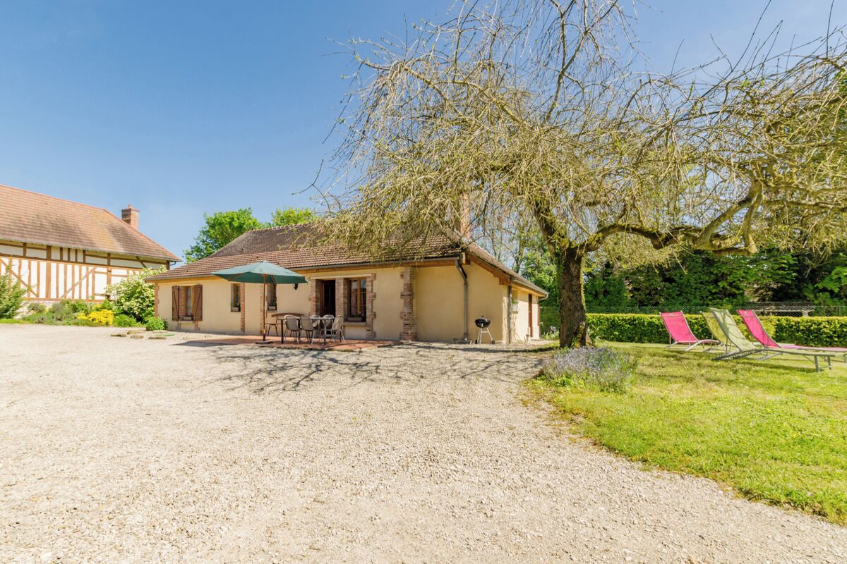 A house with a gravel driveway, a patio with outdoor furniture, and a tree in the background.