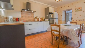 A compact kitchen with a central island, a dining area with a table and chairs, and a hexagonal patterned floor. - House (BLIGNY)