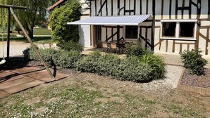 Una casa tradicional con entramado de madera, un porche cubierto, mobiliario de exterior y un columpio.