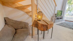 Et hyggeligt værelse med en trætrappe, et blødt siddeområde og et bord med en lampe.