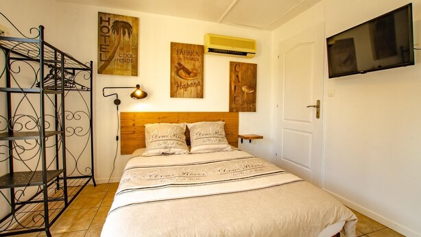 Quarto com cama, cabeceira de madeira, prateleira com abajur e arte na parede.