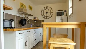 Uma cozinha com armários brancos, uma mesa de madeira e um relógio na parede.