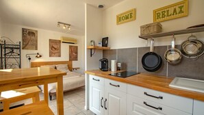 Uma cozinha compacta com mesa de madeira, armários, máquina de café e um suporte para panelas na parede.