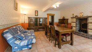 Una sala de estar acogedora con sofá, mesa de comedor, sillas, chimenea y un aparador.