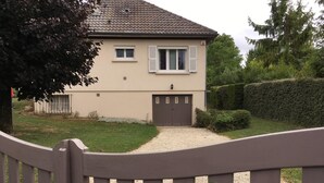 Ein Haus mit einer beige farbenen Fassade, einem dunkelbraunen Dach und einer Schotterauffahrt.