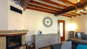 A living room with a fireplace, a clock on the wall, a sofa, and a cabinet.