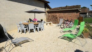 An outdoor patio with a table and chairs, a bicycle, and a brick wall.