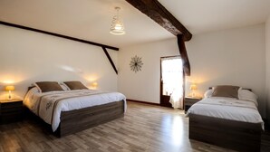 A bedroom with two beds, wooden flooring, and a sloped ceiling with exposed beams.