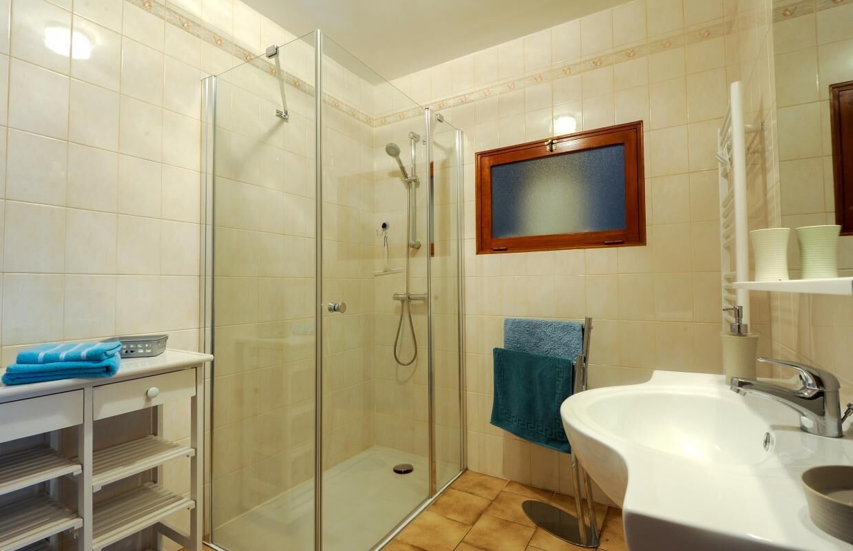 Un baño con cabina de ducha de vidrio, lavamanos y espejo.