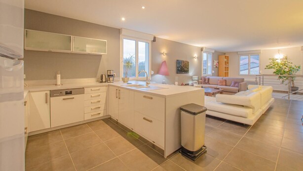 A modern kitchen with white cabinetry, a central island, and a built-in dishwasher.