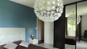 A modern bedroom with a large bed, a bedside table with a lamp, a large mirror, and a unique ceiling light fixture.