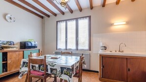 Un coin repas avec une table dressée pour quatre personnes, des chaises en bois, un meuble contenant un four à micro-ondes et une fenêtre à vitrage dépoli.