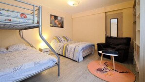 Een kamer met stapelbedden, een eenpersoonsbed, een bureau, een stoel en een rond vloerkleed met een hertenprint.