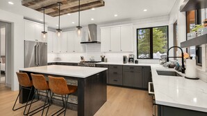 Una cocina moderna con una isla grande, electrodomésticos de acero inoxidable e iluminación colgante.