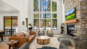 Un salón espacioso con chimenea de piedra, ventanas amplias y una zona de estar acogedora.