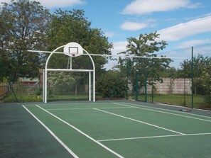 An outdoor basketball court with a hoop and a fence.