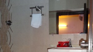 A bathroom with a white sink, a mirror, and a towel rack. - Hotel Long Stay (Ahmedabad)